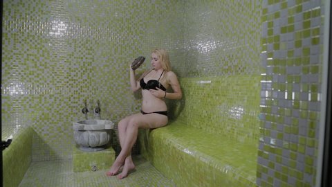 A beautiful girl pours water in a hammam. Spa treatments.