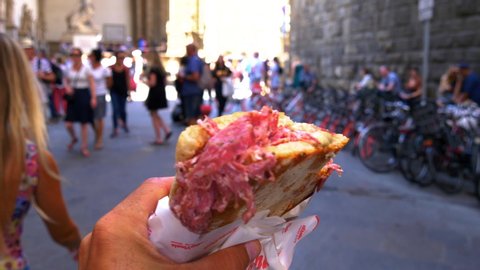 FLORENCE , TUSCANY / Italy - 06 09 2018: POV of a man walking with a Italian salami sandwich in the street of Florence, Italy