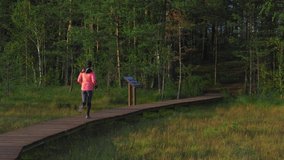 Young athletic woman running through the forest. Adventure and sport theme video