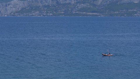 Postira, Croatia - August 2, 2019: A man paddles in a kayak on the sea. Summer time. Slow motion shot.
