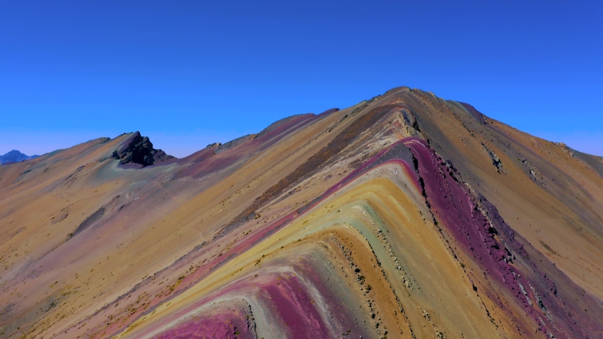 Aerial landscape of Rainbow Mountain Peak at  Vinicunca Valley. A mountain with intense red, yellow, orange, green and blue colors. Visitors on the watch point in a hilltop look them.
 Royalty-Free Stock Footage #1038335279
