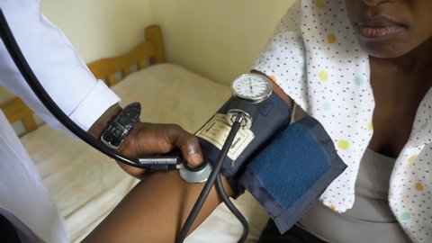 Close up shot of a sphygmomanometer and a stethoscope on an African woman's arm.