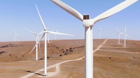 Aerial: View of large wind turbines in rural areas with high wind. blue sky and dry desert region. Global warming and green power generation concept. Australia.