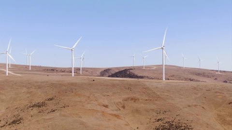 Aerial: View of large wind turbines in rural areas with high wind. blue sky and dry desert region. Global warming and green power generation concept. Australia.