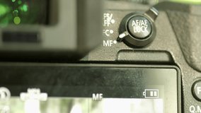 Close clip of photographer changing autofocus setting via a dial on the back of the camera