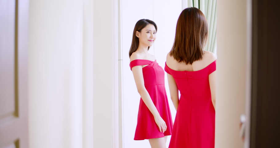 slow motion of asian girl trying red dress and looking in mirror cheerful