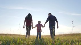 happy family father a son and mom go slow motion video concept. happy teamwork dad man mom girl lifestyle and son boy child hold hands walk go on the field in nature . happy family carefree childhood