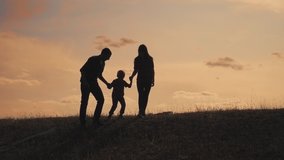 happy family father, mother and son outdoors silhouette concept slow motion video. dad man mom girl hold little boy son by hands. little boy jumping lifestyle silhouette at sunset outdoors. happy