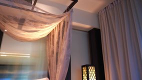 Four-poster bed with colorful pillows and sheets in hotel room. Pan and tilt. - Powered by Shutterstock - Get 15% off with code: PIKWIZARD15