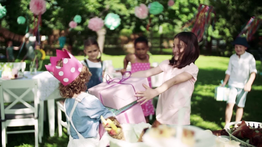 A birthday party of small girl outdoors in garden in summer, celebration concept.