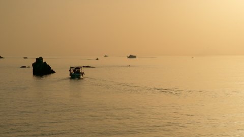 Boats sailing in the sea at golden sunset, shot in Tropea, Italy