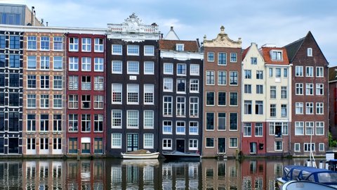 AMSTERDAM, NETHERLANDS - MAY 22, 2018: Medieval houses at Amsterdam canal at Damrak pier. Amsterdam, Netherlands. With camera pan