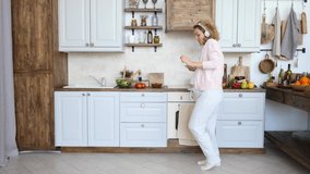 Happy Healthy Pregnancy Concept. Pregnant Woman Dancing On Kitchen With Smartphone.