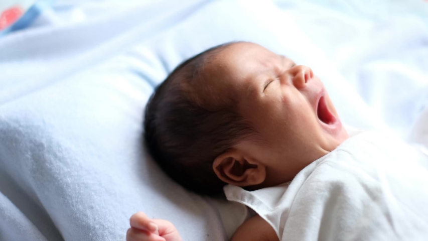 Newborn baby waking up and opening eyes. Lovely asian new born baby. Little baby boy lying on bed. Concept of caring for children and parental love. Royalty-Free Stock Footage #1038366221