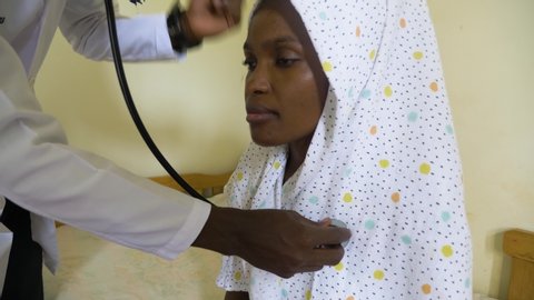 Close up shot of a African woman getting her chest checked with a stethoscope in a small medical clinic.