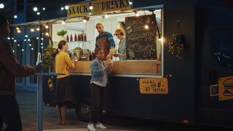 Food Truck Employee Hands Out Freshly Made Beef Burgers, Fries and Cold Drinks to Happy Young Hipster Customers. Commercial Truck Selling Street Food in a Modern Cool Neighbourhood.