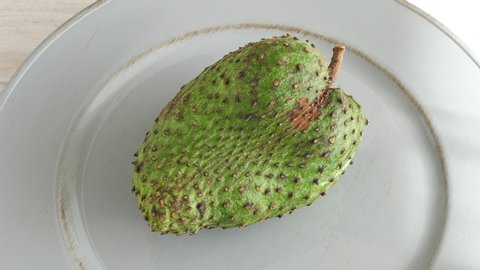 One soursop graviola, exotic, tropical fruit Guanabana on plate, Rotate