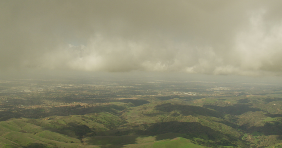 Aerial shot, day, slow lead and zoom in of southern california hills under clouds, drone