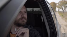 portrait of an attractive bearded man smoking a cigarette while driving a car. smoking guy in a car. 4k. 4k video. slow motion. 23.98 fps