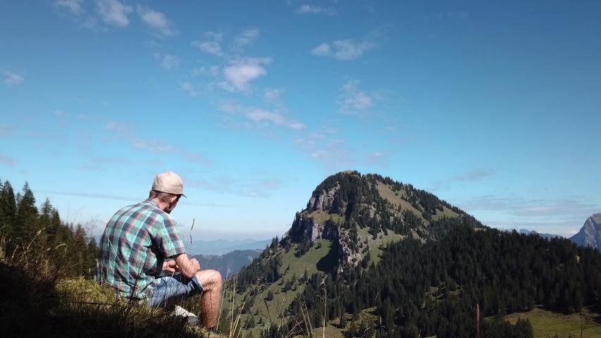 Solo traveller having lunch at Sattelegg Mountain pass in Switzerland, wide shot