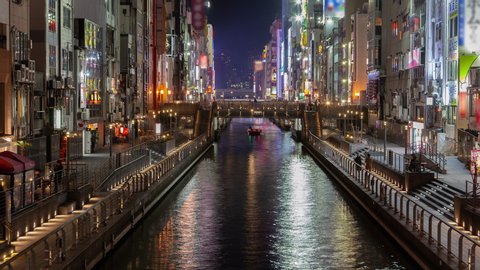 OSAKA/JAPAN - APRIL 30 2019: Timelapse zoom out Osaka Dotonbori visitor attraction on city canal banks with shops restaurants among residential blocks with outdoor advertisements on April 30 in Osaka