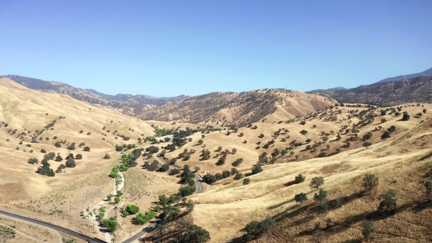 Aerial Fly Over of Winding Rural Road in Tan Foothill Mountains
