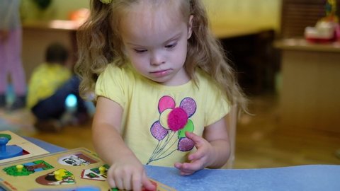 Girl with down syndrom developing motor skills in rehab center for special children