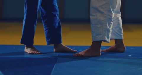 Legs of athletes on the tatami. Wrestlers make sweeps with their feet. View from below.