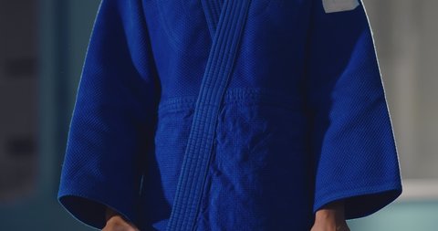 Girl-athlete is tying a black belt in a knot, preparing for training. Close-up.