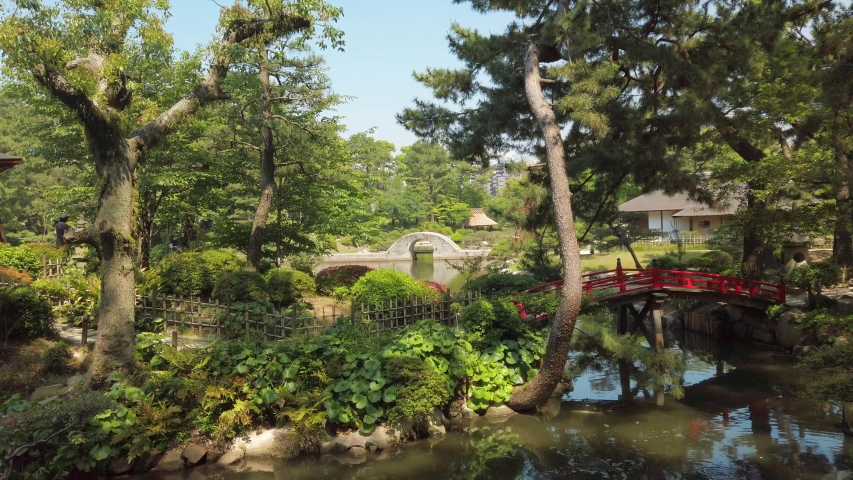 Japanese Garden Shukkei-en in Hiroshima, with a pond and a red bridge in may.