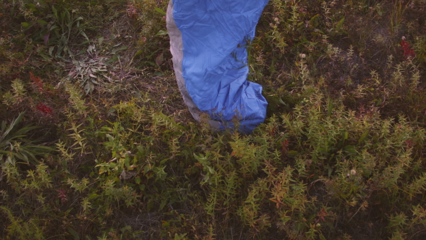 Young Caucasian woman jumping in sleeping bag at sunset in the forest. Recorded in Raw on Blackmagic camera.