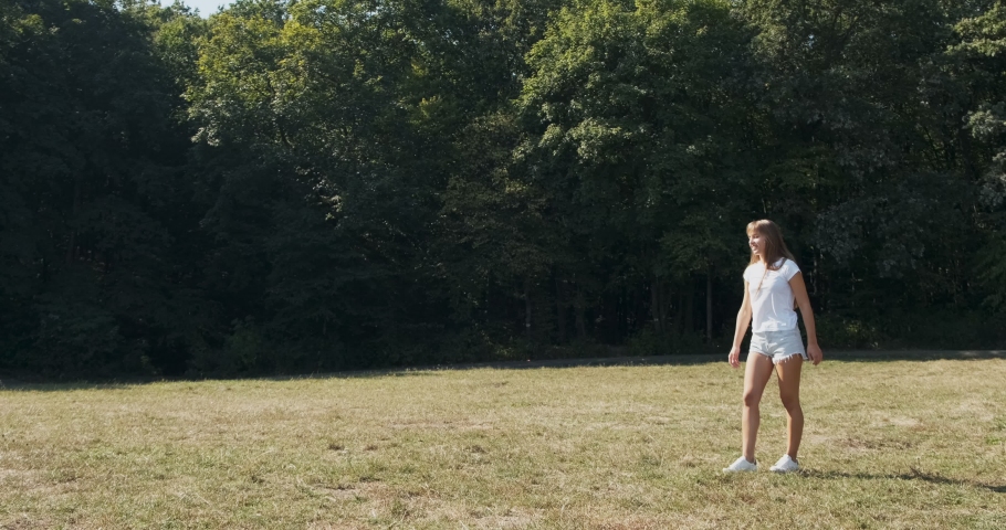 Happy atractive female jumping on meadow at summer. Slow motion