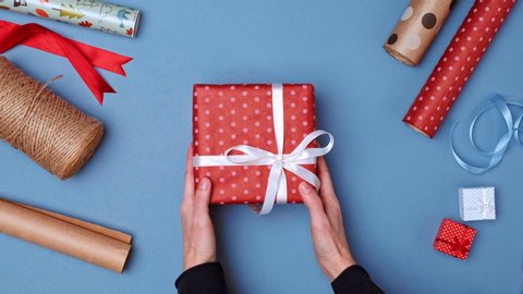 Male hands giving present to woman. Man holding many wrapped gifts and female hands taking box. Colorful blue holidays background with assortment of gift boxes, Christmas packaging, wrapping paper.