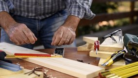 Adult carpenter craftsman with a pencil and the carpenter's square trace the cutting line on a wooden table. Construction industry, housework do it yourself. Footage slow motion.