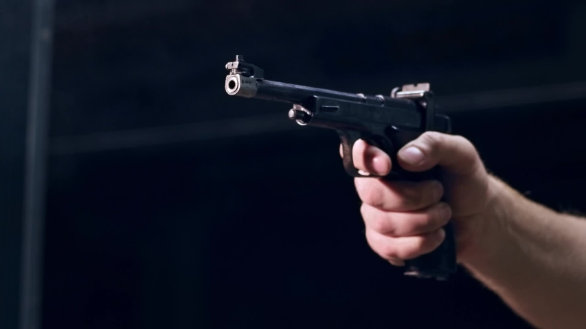 Shooting gallery. A young man preparing the gun and shooting with a firearms. A smoking gun. A concentrated young man shooting on a shooting range. Spark. Bullet. Shot.