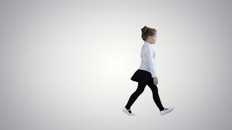 Beautiful little girl in dress walking by on gradient background.