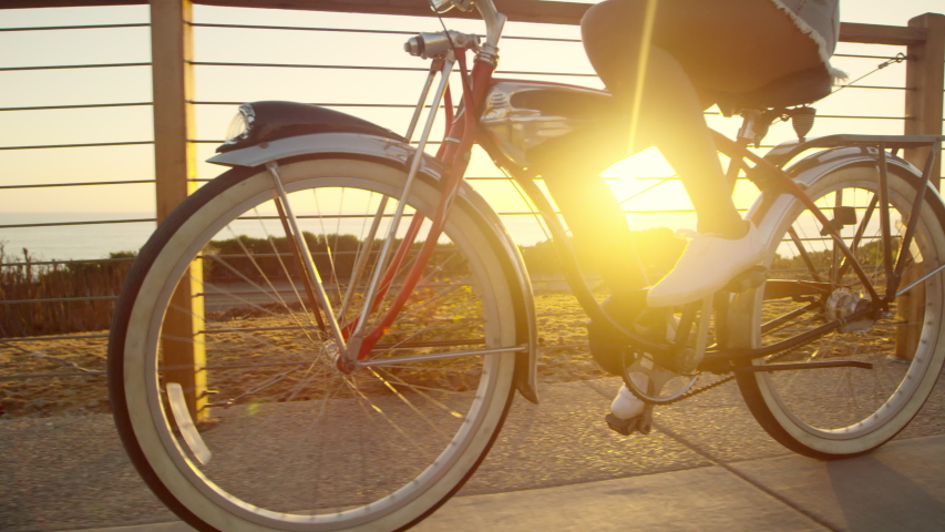 Slow motion young girl riding beach cruiser bike at sunset with lens flare  Royalty-Free Stock Footage #1038443660