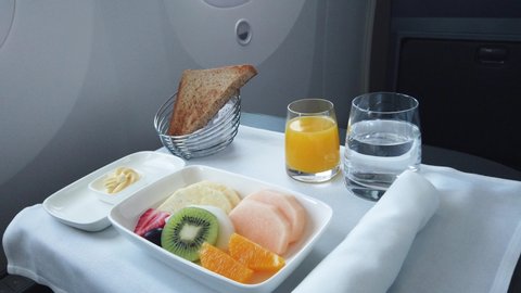 Delicious breakfast with fruit served on board of business class airplane. Tray of food in the airplane. Tray of food on the plane, business class travel. 
