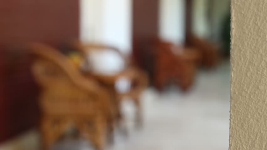 Changing focus to a resort hallway with wicker chairs in front of the rooms.