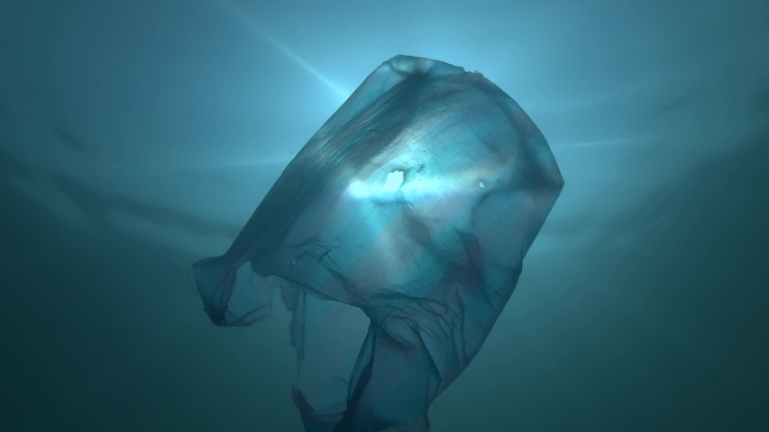 Plastic pollution, used blue plastic bag slowly drifting underwater in the sun lights. Low-angle shot, Backlighting. Plastic debris underwater. Plastic garbage environmental pollution problem  Royalty-Free Stock Footage #1038458462