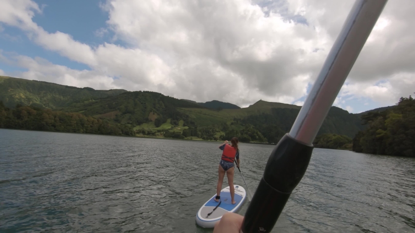 Sup pov of boy and girl in green lake lagoa verde