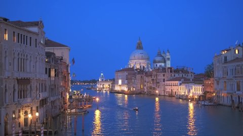 View of Venice Grand Canal with boats and Santa Maria della Salute church in the evening from Ponte dell'Accademia bridge. Venice, Italy. Zoom in effect