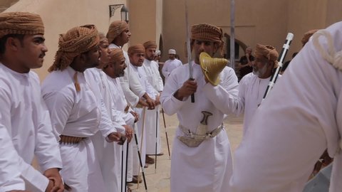 Nizwa, Oman, - February 2019. Arab musicians in traditional white clothes play various musical instruments. Presentation for visitors to the fortress.