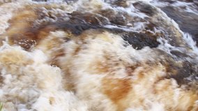 4K slow motion video of dirty river water. Brown muddy water. Pollution in Dumfries in Scotland, UK. Ecological problem. Nature full hd video. Close up of fast flowing river in slow motion.