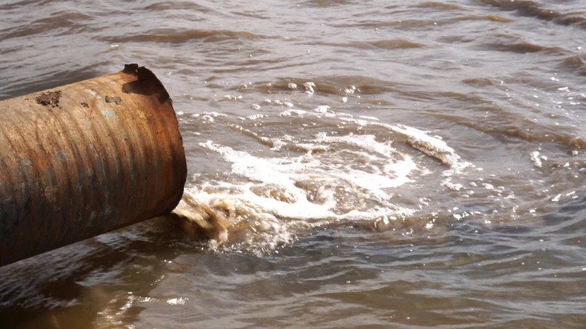 Water pollution. Wastewater is discharged through a rusty sewer into a body of water. Royalty-Free Stock Footage #1038482981