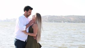 In-love and happy mixed race couple. Caucasian blonde woman and Turkish (Middle Eastern) man in love at the beach. Husband lovingly touching the hair and face of his wife. 4K video. Honeymoon.