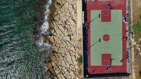 Aerial drone top down video of seaside basketball court in popular exotic island