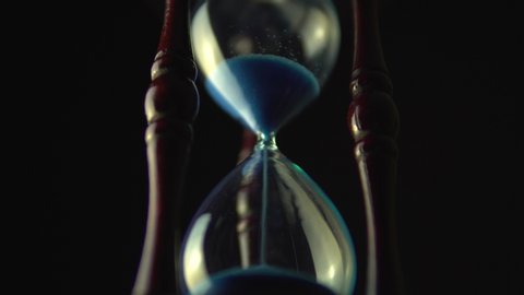Sand move through hour glass. Close up of hourglass clock. Old time classic sandglass timer. Closeup sand is flowing down the bottom.