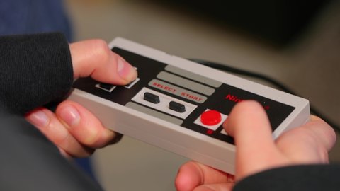 BUDAPEST, HUNGARY - FEBRUARY 17, 2018: Playing the classic Nintendo NES console from the 80s, controller closeup, Super Mario 3 gameplay.