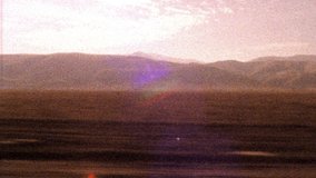 Shaky old looking archival footage drving on 101 highway towards Los Angeles approaching LA sign as sun sets in the distance
